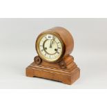 A walnut effect oblong based mantel clock, the drum set dial set on two scrolls and a stepped base