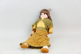 An Armand Marseille bisque headed doll with brown ringlet wig, blue rolling glass eyes (one
