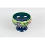 A Moorcroft pottery pedestal bowl decorated with a blue green ground and tube line band of flowers