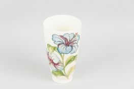 A Moorcroft pottery cream ground tapering vase, tube line decorated in hibiscus pattern with