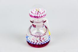A Perthshire millefiori glass bottle paperweight with mottled ruby base colour, multi-coloured