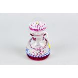 A Perthshire millefiori glass bottle paperweight with mottled ruby base colour, multi-coloured