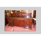 A high Victorian carved four door inverted front sideboard, the raised panel back with excellently