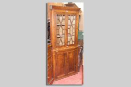 A Georgian oak and elm two piece corner cupboard, the top with chamfered cornice above twin thirteen