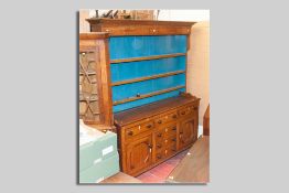An antique oak straight front Anglesey dresser, three shelf rack over a base of three opening