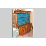 An antique oak straight front Anglesey dresser, three shelf rack over a base of three opening