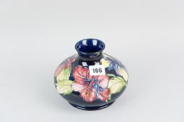 A good Moorcroft pottery squat form vase having deep blue colour body with tube lined hibiscus