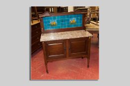 An Edwardian mahogany tile topped washstand with pink marble surface, the tile back with Majolica