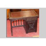 A small early 20th Century carved oak single pedestal desk, the kneehole having an open spindle