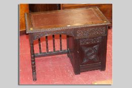 A small early 20th Century carved oak single pedestal desk, the kneehole having an open spindle