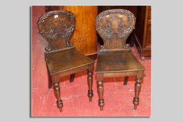 A pair of Victorian shield back oak hall chairs, a leaf carved back with central shield cartouche,