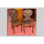 A pair of Victorian shield back oak hall chairs, a leaf carved back with central shield cartouche,