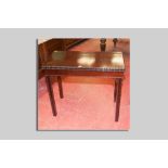 An Edwardian mahogany flip top card table with carved edge moulding, inverted chamfered legs with