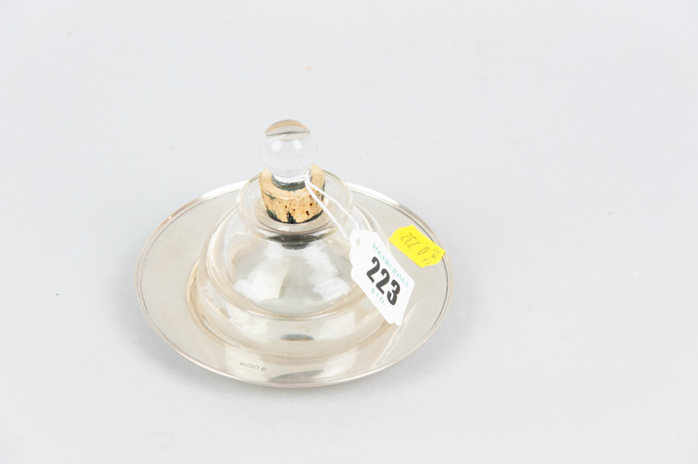 An heavy glass inkwell on a circular silver dish, 1.3ozs, Sheffield 1922