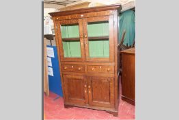 A Welsh oak one piece bookcase having two upper plain glazed doors over two opening drawers and