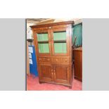 A Welsh oak one piece bookcase having two upper plain glazed doors over two opening drawers and