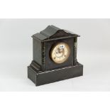 A black slate oblong based mantel clock with green mottled pillars either side of the circular