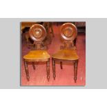 An interesting pair of Victorian mahogany plate back hall chairs, the dished round back with round