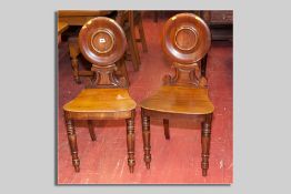 An interesting pair of Victorian mahogany plate back hall chairs, the dished round back with round