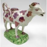 SWANSEA pottery - pearlware cow creamer decorated with pink lustre patches and standing on a grass-
