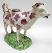 SWANSEA pottery - pearlware cow creamer decorated with pink lustre patches and standing on a grass-