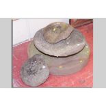 An antique circular grindstone, 30 cms diam, another 21 cms diam and two pieces of stone