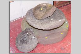 An antique circular grindstone, 30 cms diam, another 21 cms diam and two pieces of stone