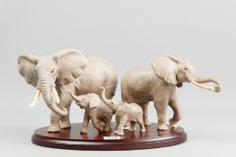 A group of four matt glazed model elephants, two elephants with their calves by Lennox on an oval