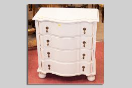A neat white painted pine Jacobean style serpentine fronted chest of four long drawers, all with