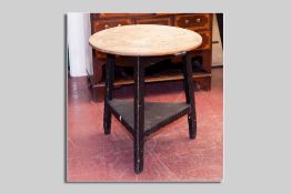 An antique pine cricket table with under tier shelf, 70 cms high, 65.5 cms diam