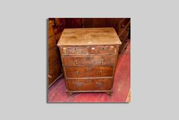 A walnut veneered oak and pine chest of three long and two short drawers, all with brass escutcheons