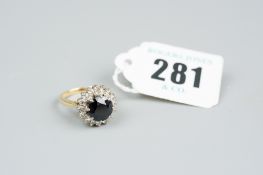 An eighteen carat gold sapphire and diamond cluster ring, a three carat round cut sapphire having
