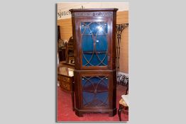 An early 20th Century mahogany two piece standing corner cupboard, each section having a glazed door