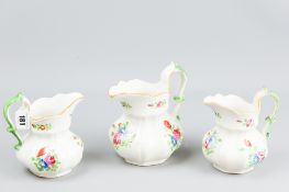 A graduated set of three Swansea pottery segmented jugs, hand painted floral sprays with green