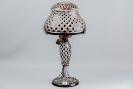 A ruby overlaid and cut glass waisted column lamp with starburst cut domed shade, the shade on a