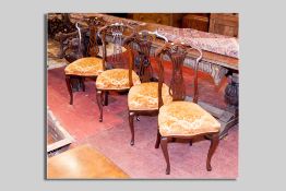 A set of four late 19th/early 20th Century mahogany dining chairs having carved swept  top rails