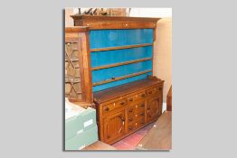 An antique oak straight front Anglesey dresser, three shelf rack over a base of three opening