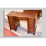 A neat reproduction mahogany serpentine front kneehole desk with tooled leather top having a