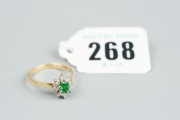 An eighteen carat gold emerald and diamond ring in a star cluster having an oval emerald with