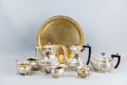 A circular brass tray with a four piece electroplated tea and coffee service and a three piece
