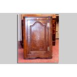 An antique oak single door hanging cupboard having a sunburst inlay and with a shaped and field