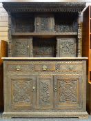 A carved oak tridarn, the base with two cupboards beneath three drawers, the top section with two