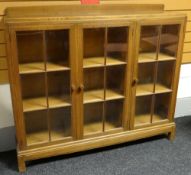 A Brynmawr 'Gower Dwarf' oak bookcase having a rail top and three glazed doors, 137cms wide, circa