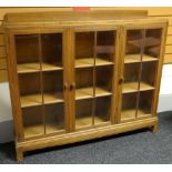 A Brynmawr 'Gower Dwarf' oak bookcase having a rail top and three glazed doors, 137cms wide, circa