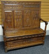 An English oak box-seat settle, the base and high back profusely carved to the front and back with