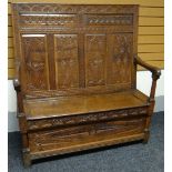 An English oak box-seat settle, the base and high back profusely carved to the front and back with