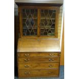 An oak bureau-bookcase, the base with four graduated drawers and hinged slope revealing a fitted