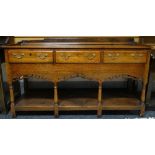 An oak dresser base with open plank shelf, pierced apron to four baluster supports and with three