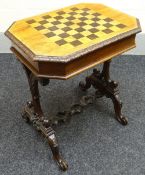 A multi-wood chequer top table on ornate supports and with Black Forest style naturalistic carved