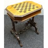 A multi-wood chequer top table on ornate supports and with Black Forest style naturalistic carved